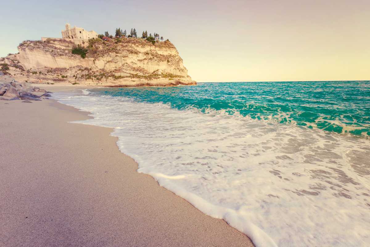 Spiaggia di Tropea con il mare cristallino e il Santuario sullo sfondo